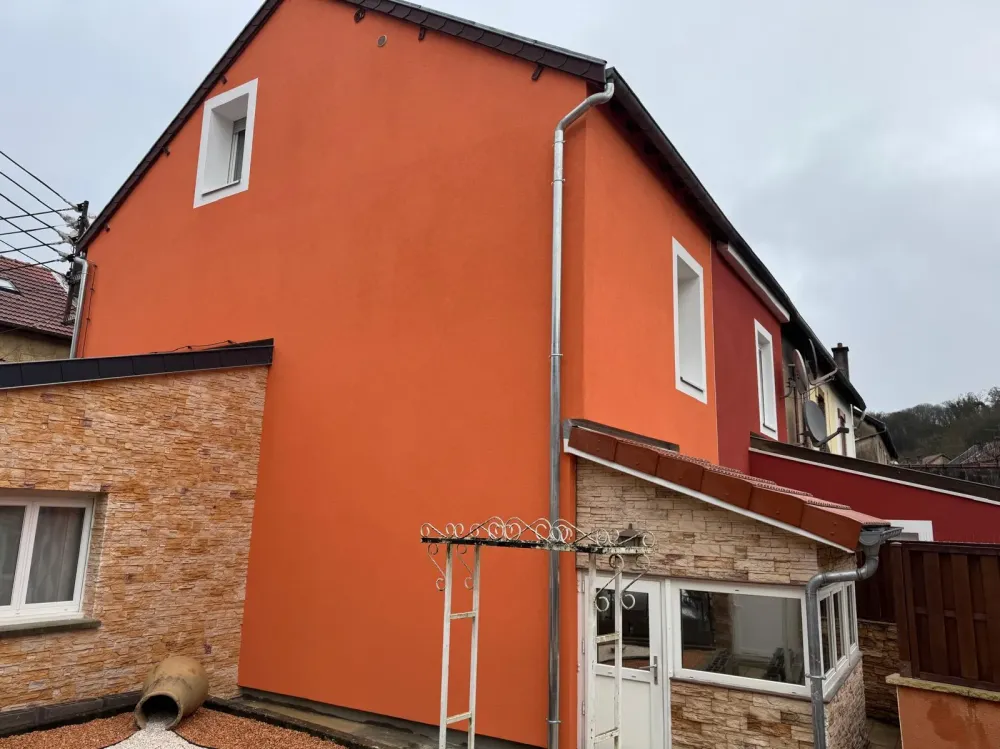 Maison aux murs orange et toit, se tenant dans un environnement lumineux